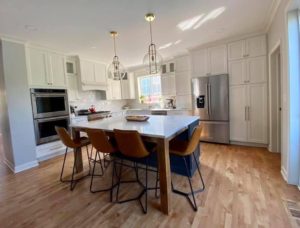 Beautiful transitional inspired kitchen with brushed gold accents, Sherwin Williams Iron Ore island and Calacatta Monaco Quartz counters